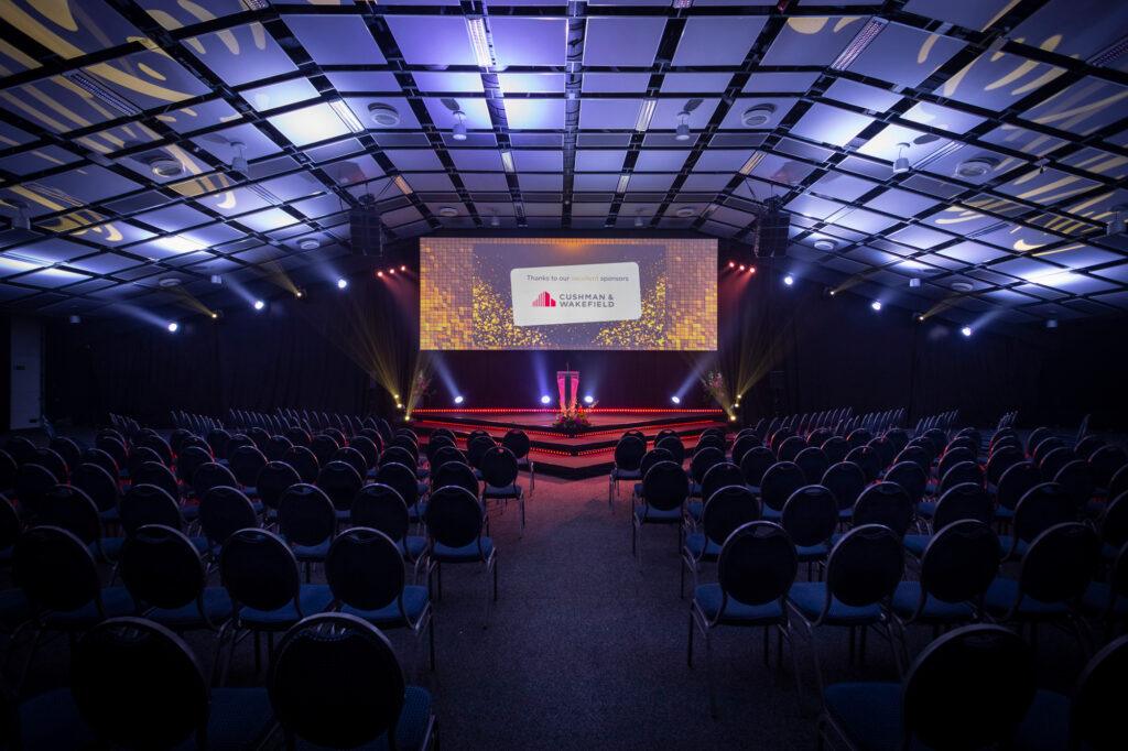 Congres locatie Hercules bij De Montil met podiumopstelling en sfeerverlichting.