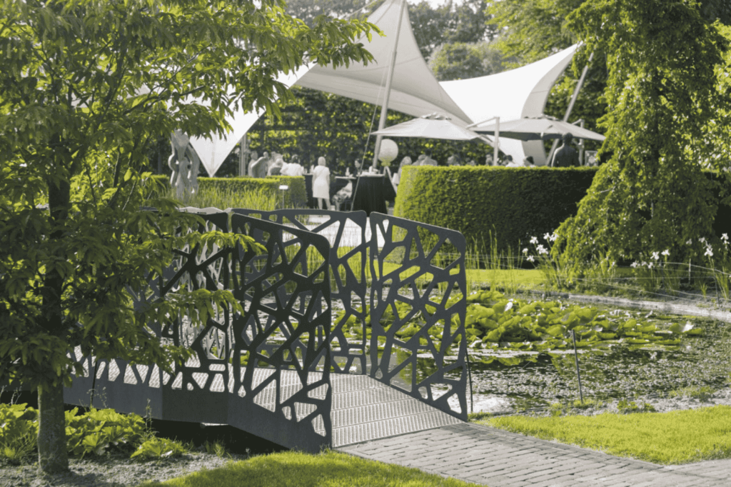 Decoratieve brug in kunstzinnige tuin bij De Montil, ideaal voor outdoor events.