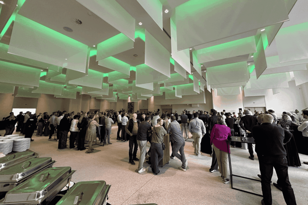 Netwerkevenement in zaal Andromeda van De Montil, onder groene sfeerverlichting.