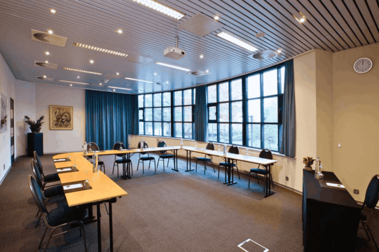 Vergaderruimte met U-opstelling, beamer en whiteboard.