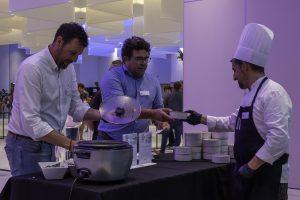 Collega’s scheppen samen eten op bij een cateringstand tijdens een bedrijfsfeest en genieten van een informele netwerksfeer.
